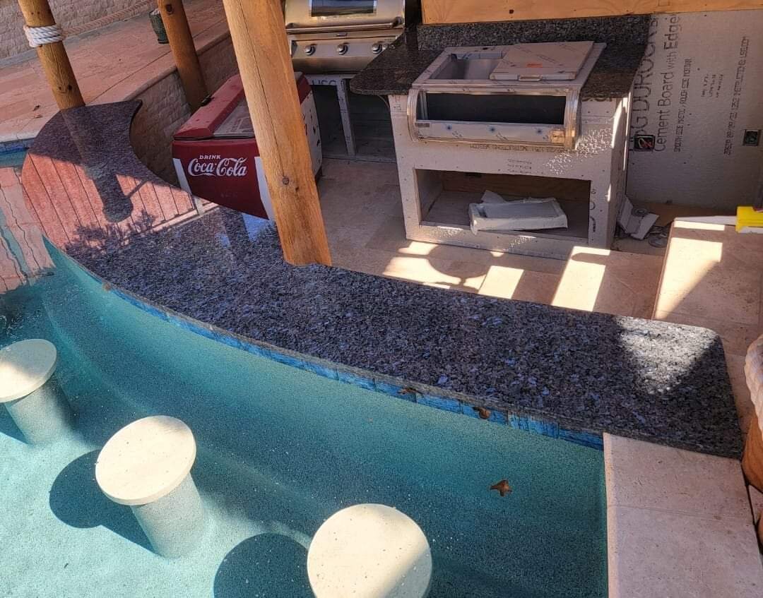 Curved blue granite swim-up bar beside a pool