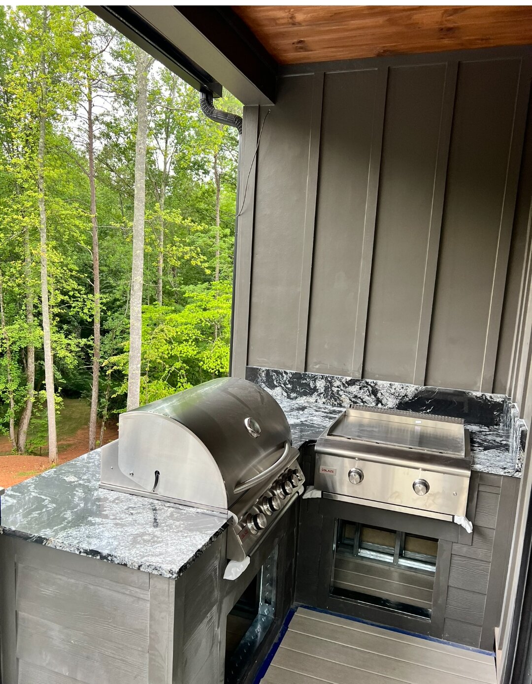 Outdoor kitchen with black-and-white stone counters, built-in grill, and griddle