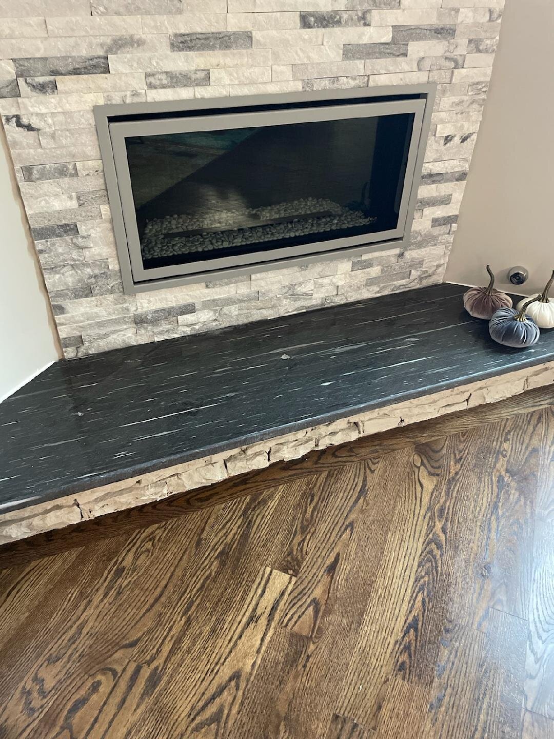 Black granite fireplace hearth below a stacked-stone surround