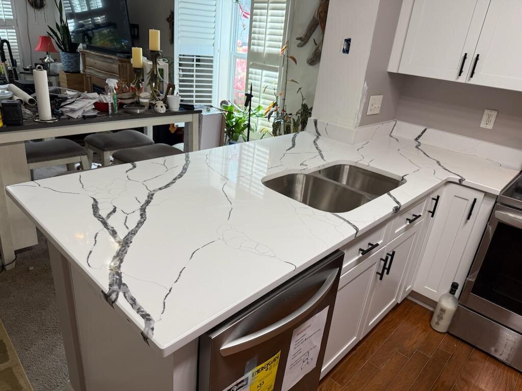 White kitchen with a bold veined stone countertop and undermount sink