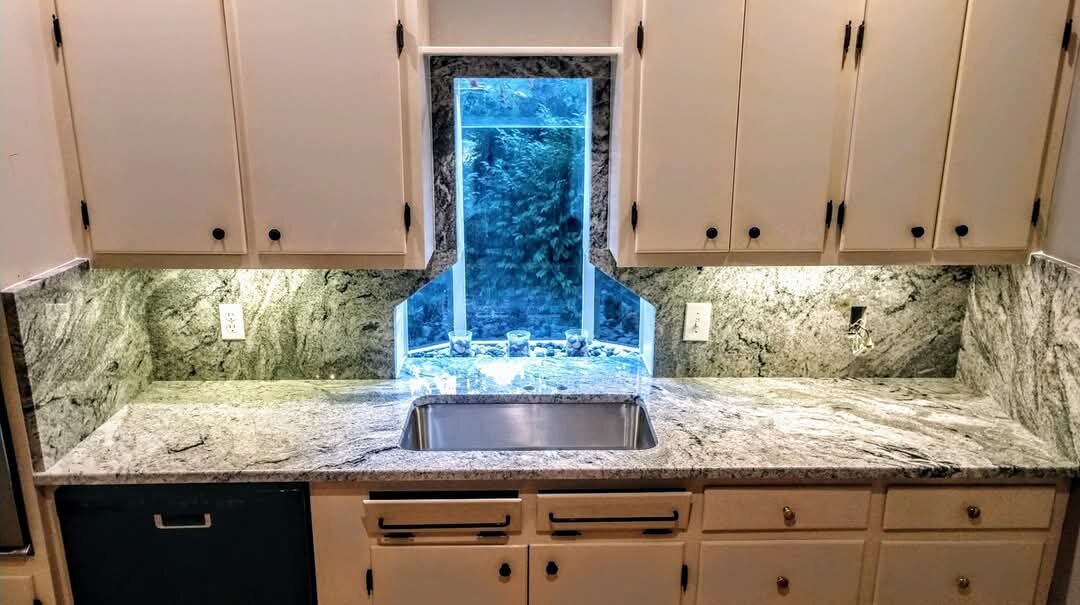 Green-gray granite counters and backsplash framing a garden window