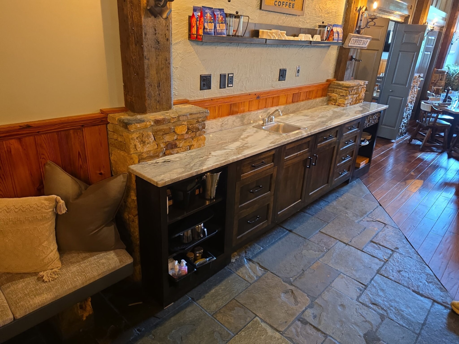 Restaurant service counter with natural stone surface, sink, and dark cabinetry