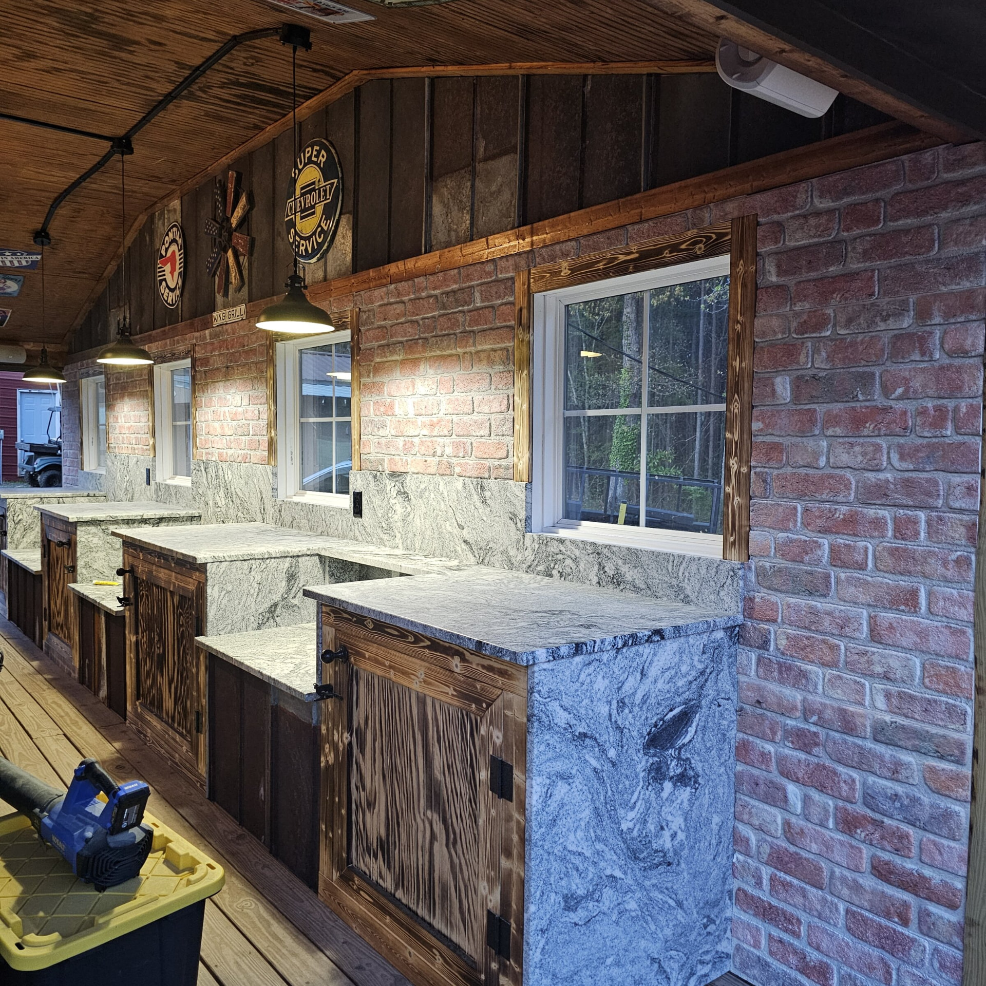 Swirled granite serving counters with rustic wood cabinets along a brick restaurant wall