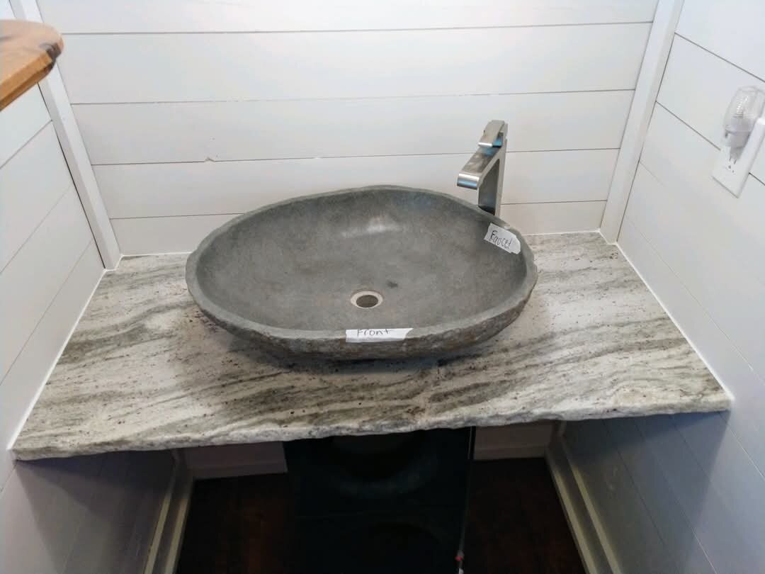 Compact natural stone vanity topped with a round vessel sink