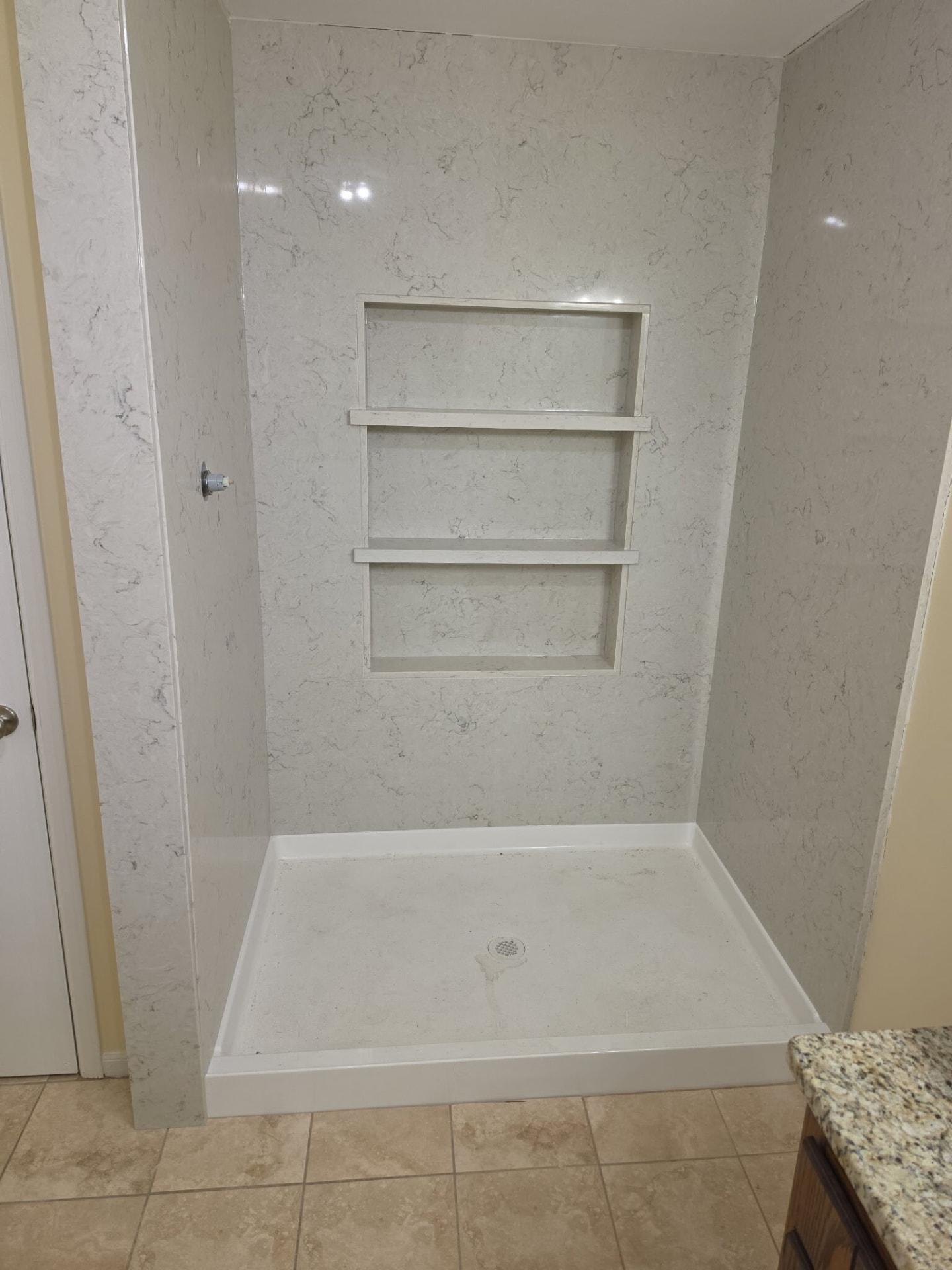 White quartz shower walls with a built-in recessed shelf niche
