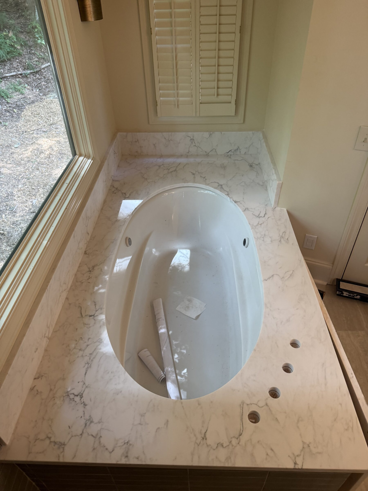 White marble-look tub deck with an undermount oval tub