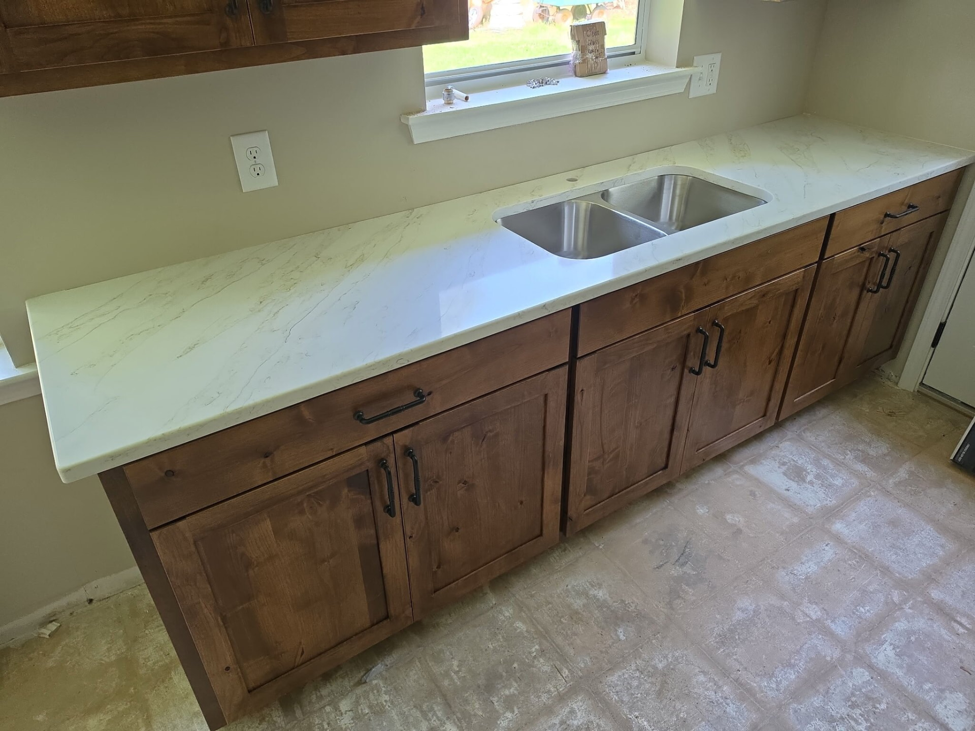 White quartz counter with double sink over rustic alder cabinets