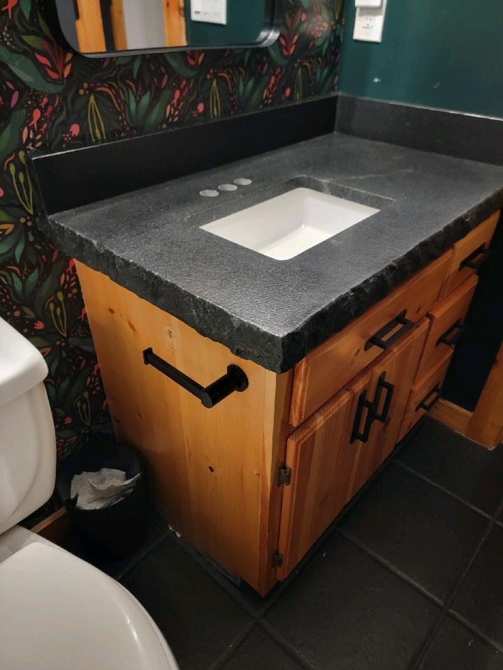 Dark textured stone vanity with an undermount sink and natural wood cabinetry