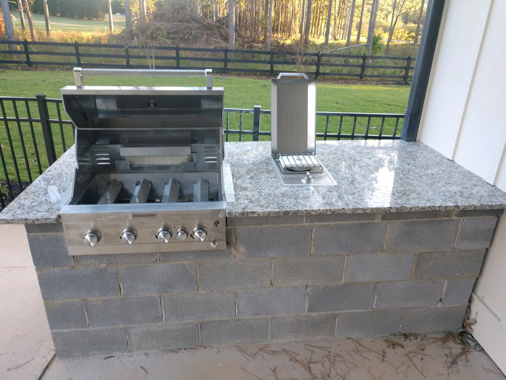 Outdoor grill station with a polished granite countertop and built-in stainless appliances