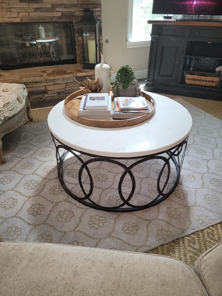 Round white stone coffee table on a black iron base