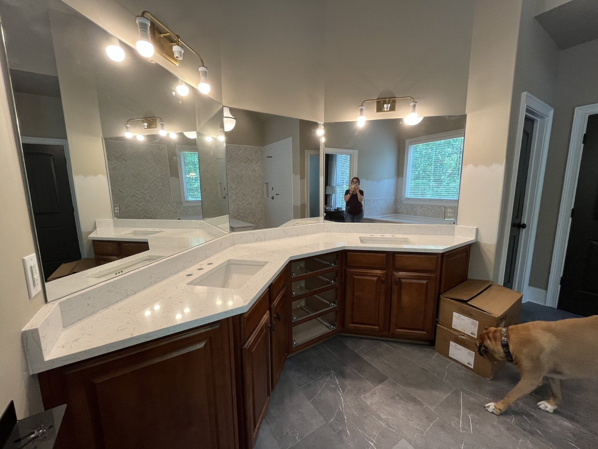 Large angled white stone bathroom vanity with wood cabinetry