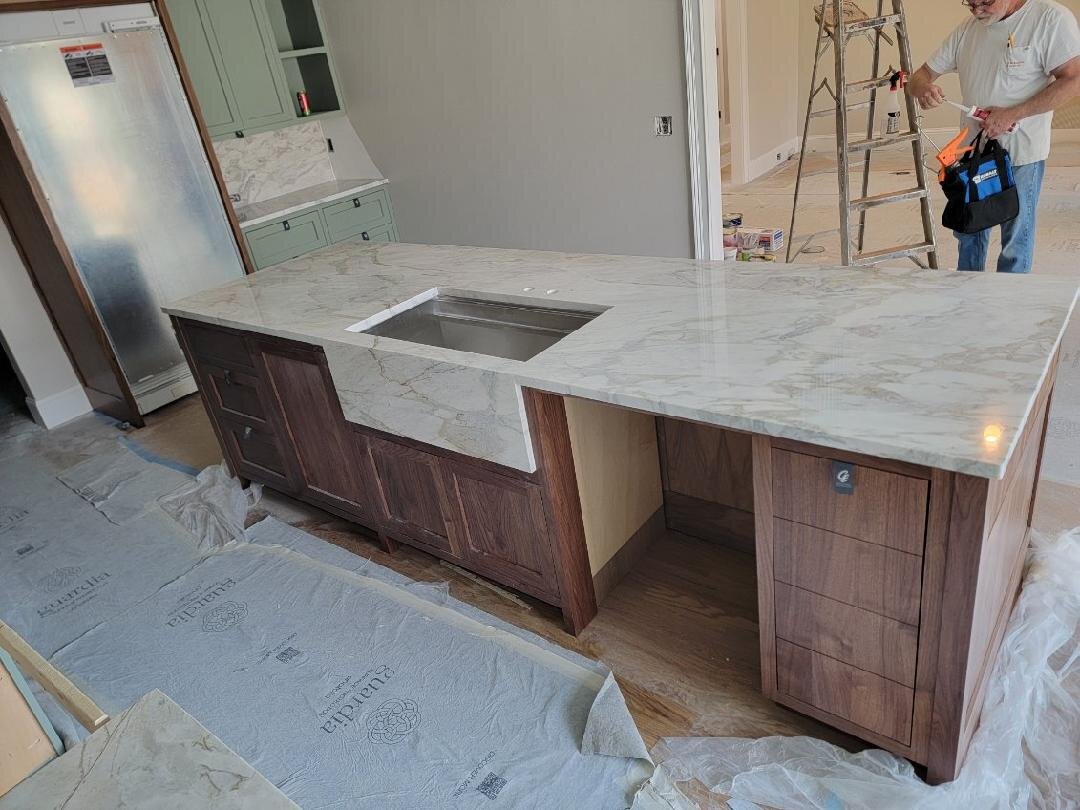 Long marble island over walnut cabinets during install