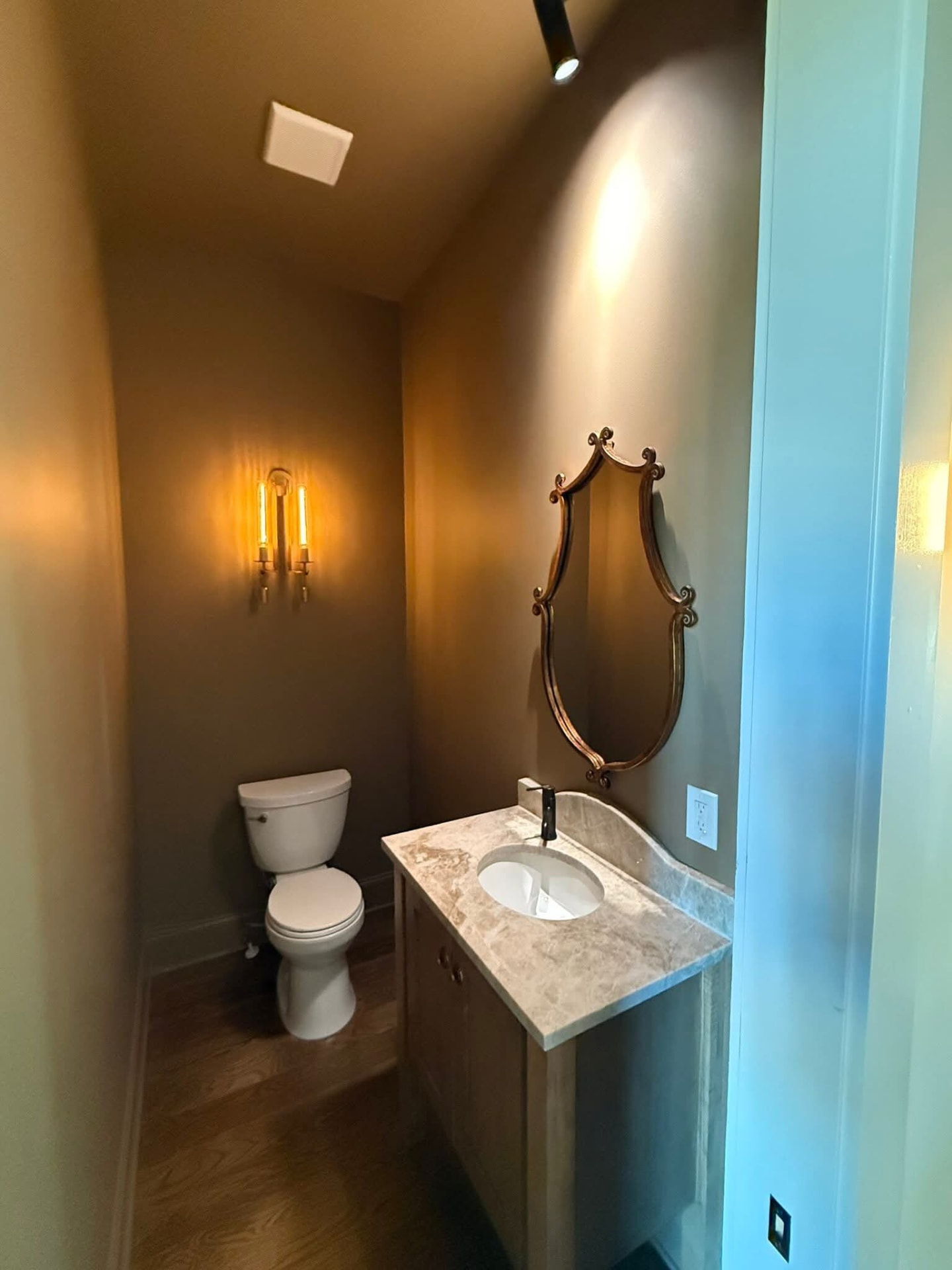 Powder room vanity with a warm beige marble top and curved backsplash