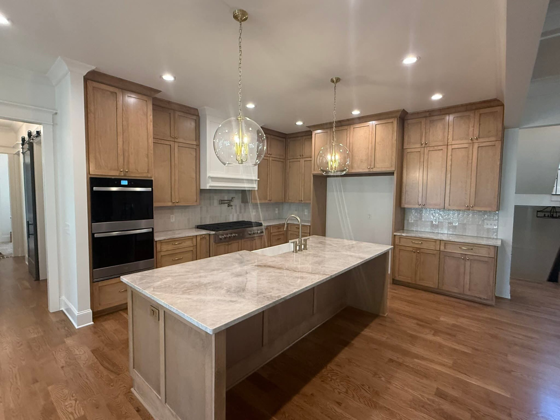 Quartzite waterfall island with warm wood cabinets