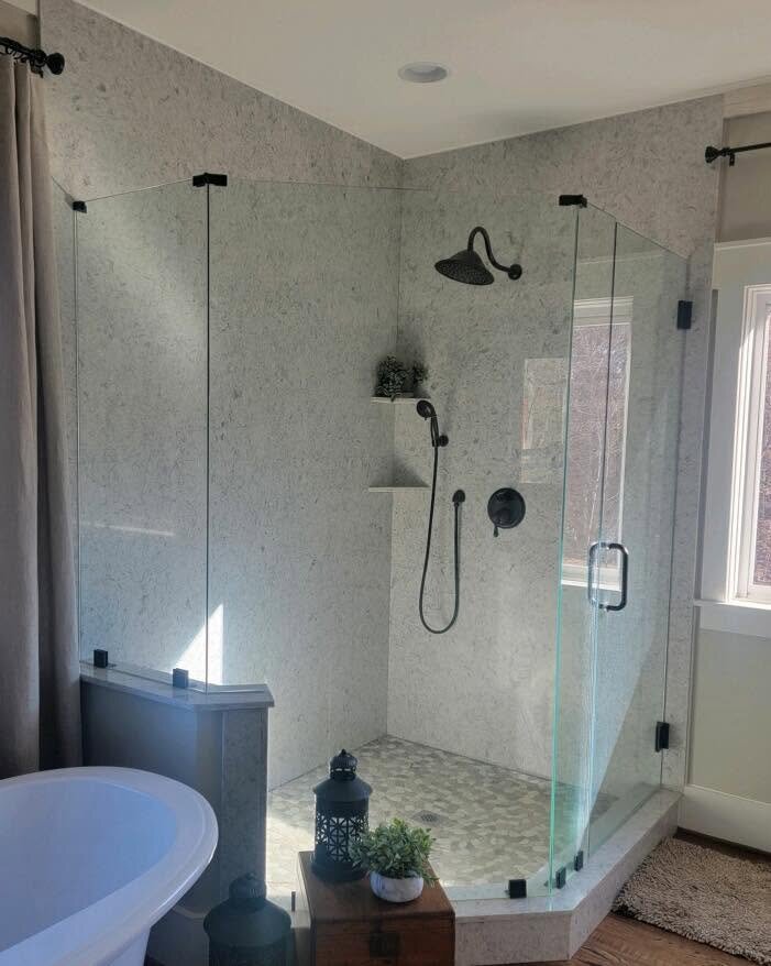 Corner glass shower with stone wall panels and pebble floor